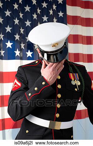 Stock Image - Serviceman in dress blues by US flag. Fotosearch
