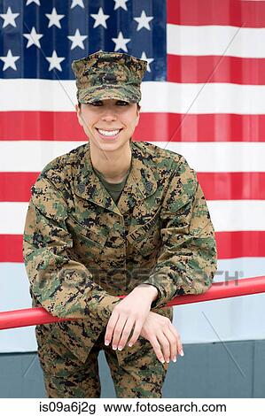 Stock Image - Servicewoman in camouflage by US flag. Fotosearch