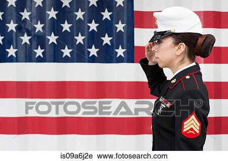 Stock Image - Servicewoman in dress blues by US flag. Fotosearch