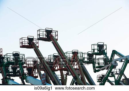 Stock Image - Silhouette of cherry pickers against sky. Fotosearch