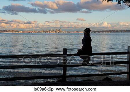 Stock Photography - Silhouette of woman sitting on fence. Fotosearch