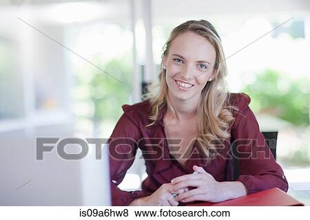 Stock Photo - Smiling businesswoman sitting at desk. Fotosearch