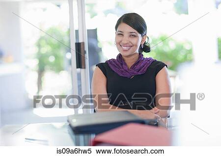 Stock Photography - Smiling businesswoman sitting at desk. Fotosearch