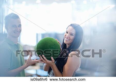Stock Photograph - Smiling couple holding green ball. Fotosearch