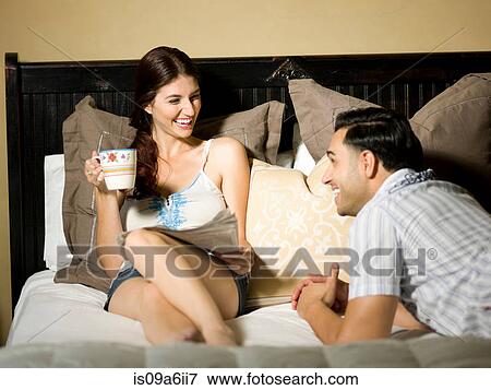 Stock Photo - Smiling couple relaxing on bed. Fotosearch