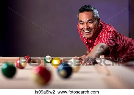 Stock Image - Smiling man playing pool. Fotosearch