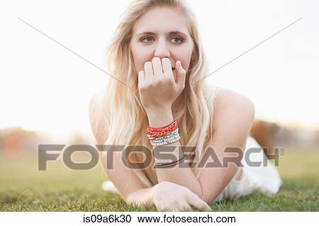 Stock Image - Smiling woman laying in grass. Fotosearch