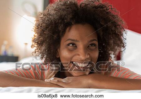 Stock Photo - Smiling woman laying on bed. Fotosearch