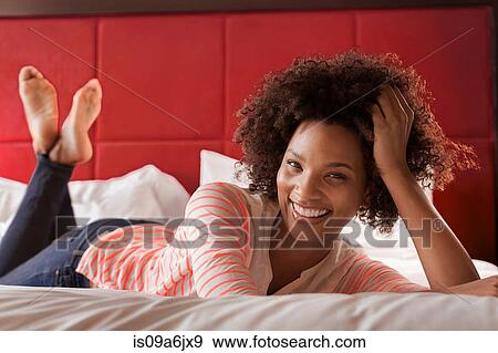 Stock Photo - Smiling woman laying on bed. Fotosearch