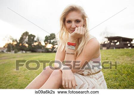 Stock Photograph - Smiling woman sitting in field. Fotosearch