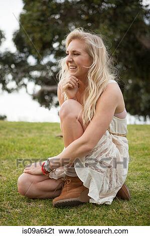 Stock Photograph - Smiling woman sitting in field. Fotosearch