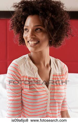 Smiling woman sitting on bed View Large Photo Image Stock Photo - Smiling woman sitting on bed. Fotosearch