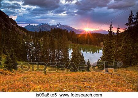 Sun setting over still rural lake View Large Photo Image Stock Photography - Sun setting over still rural lake. Fotosearch
