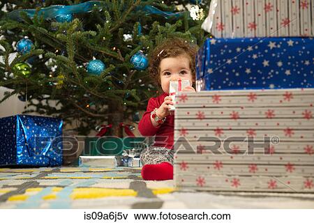 Stock Photo - Toddler girl opening Christmas gifts. Fotosearch