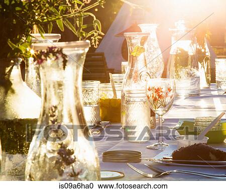 Stock Image - Water and herbs on set table outdoors. Fotosearch