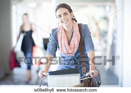 Stock Photograph - Woman carrying box in bicycle basket. Fotosearch