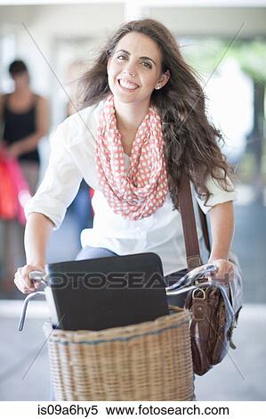 Stock Photography - Woman carrying box in bicycle basket. Fotosearch