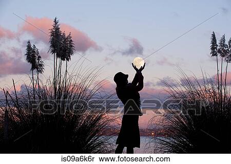 Stock Photography - Woman cupping hands around moon. Fotosearch