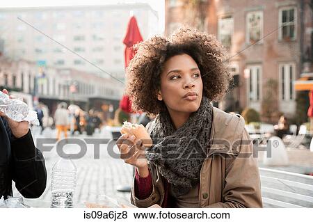 Stock Photo - Woman eating on city street. Fotosearch