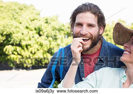 Stock Photo - Woman feeding boyfriend fruit outdoors. Fotosearch