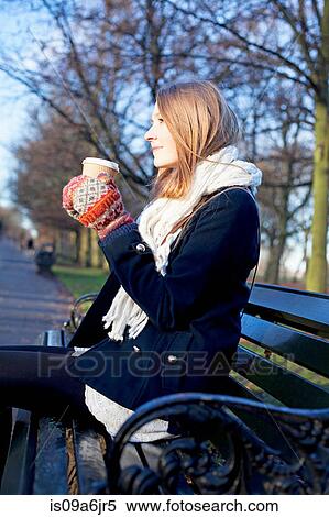 Stock Photography - Woman having coffee on park bench. Fotosearch