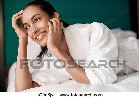 Stock Image - Woman in bathrobe laying on bed. Fotosearch