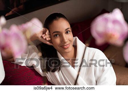 Picture - Woman in bathrobe sitting on sofa. Fotosearch