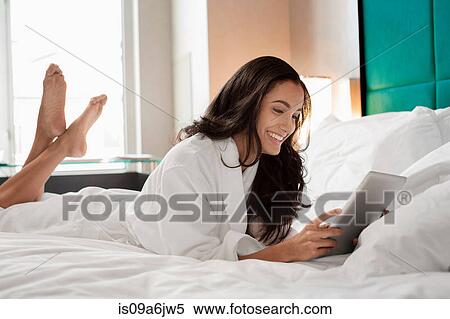 Stock Photography - Woman in bathrobe using tablet computer. Fotosearch