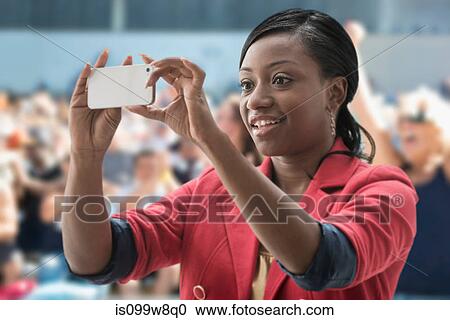 Woman in stadium, recording event with her phone View Large Photo Image Stock Image - Woman in stadium, recording event with her phone. Fotosearch