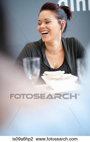Stock Image - Woman laughing at dinner table. Fotosearch