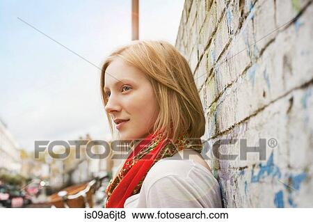 Stock Photo - Woman leaning on brick wall. Fotosearch