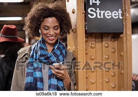 Woman listening to earphones at station View Large Photo Image Stock Photo - Woman listening to earphones at station. Fotosearch