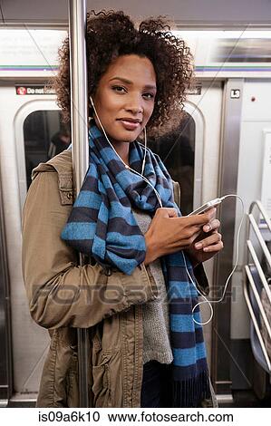 Woman listening to earphones on subway View Large Photo Image Stock Image - Woman listening to earphones on subway. Fotosearch