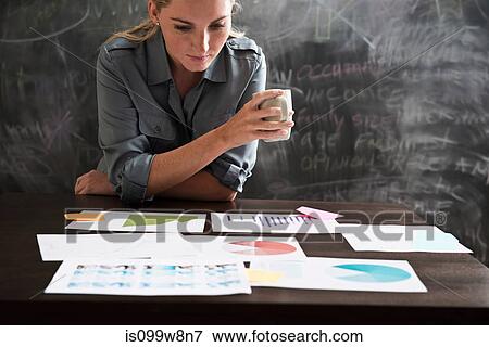 Woman looking at papers with cup of coffee View Large Photo Image Stock Photo - Woman looking at papers with cup of coffee. Fotosearch
