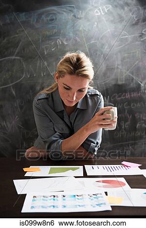 Stock Photograph - Woman looking at papers with cup of coffee. Fotosearch