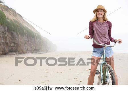 Stock Photo - Woman on bicycle on beach. Fotosearch