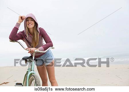 Stock Photograph - Woman on bicycle on beach. Fotosearch