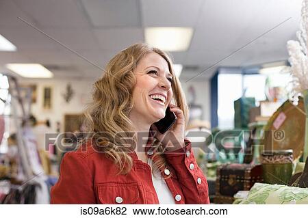 Woman on cell phone in thrift store View Large Photo Image Stock Image - Woman on cell phone in thrift store. Fotosearch