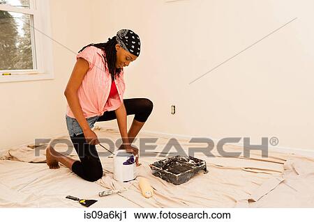 Stock Image - Woman painting in new home. Fotosearch