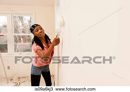 Stock Image - Woman painting in new home. Fotosearch