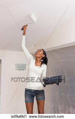 Stock Image - Woman painting in new home. Fotosearch