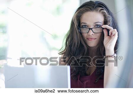 Stock Image - Woman peering over eyeglasses. Fotosearch