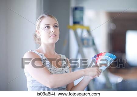 Stock Photograph - Woman picking paint swatches in home. Fotosearch