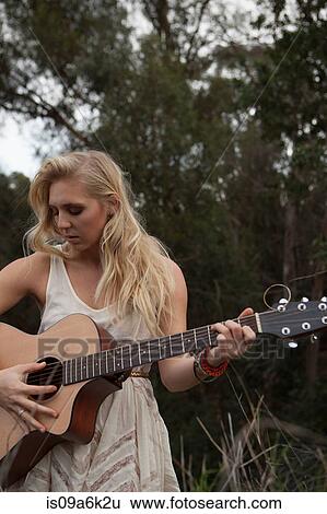 Stock Photograph - Woman playing guitar in forest. Fotosearch