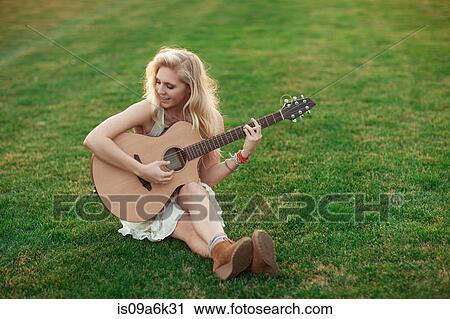 Woman playing guitar in grass View Large Photo Image Stock Image - Woman playing guitar in grass. Fotosearch