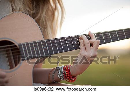 Woman playing guitar in grass View Large Photo Image Stock Image - Woman playing guitar in grass. Fotosearch