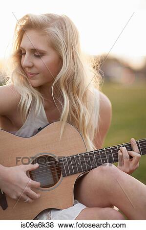 Woman playing guitar in grass View Large Photo Image Stock Photo - Woman playing guitar in grass. Fotosearch