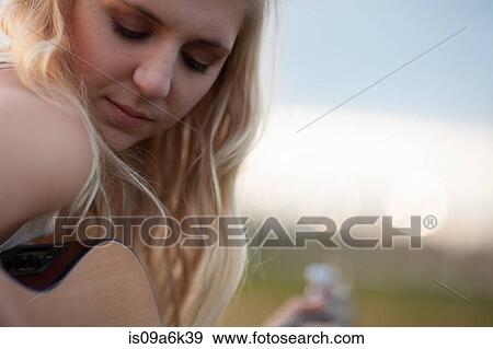 Stock Photo - Woman playing guitar outdoors. Fotosearch