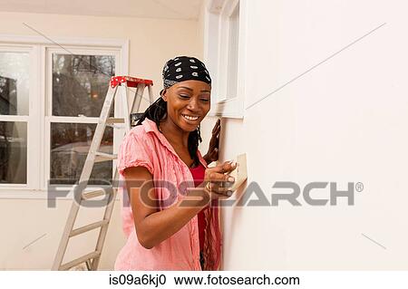 Woman priming wall in new home View Large Photo Image Stock Image - Woman priming wall in new home. Fotosearch