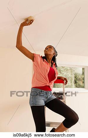 Woman priming wall in new home View Large Photo Image Stock Photography - Woman priming wall in new home. Fotosearch